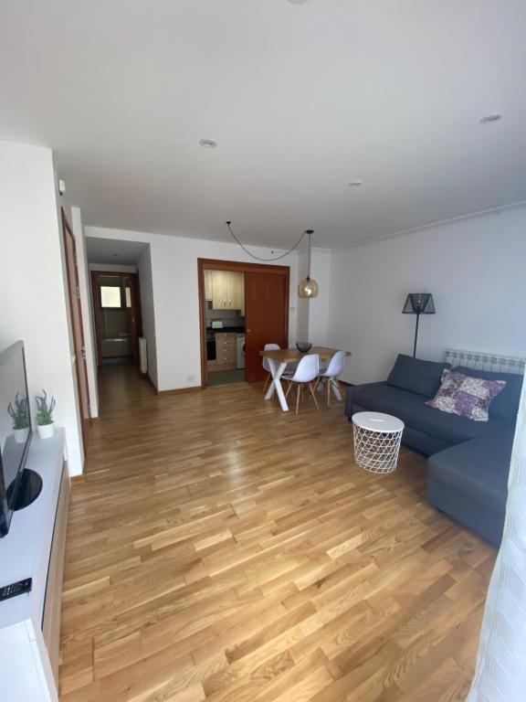 a living room with a blue couch and a wooden floor at Apartament Acollidor a Ribes de Freser in Ribes de Freser