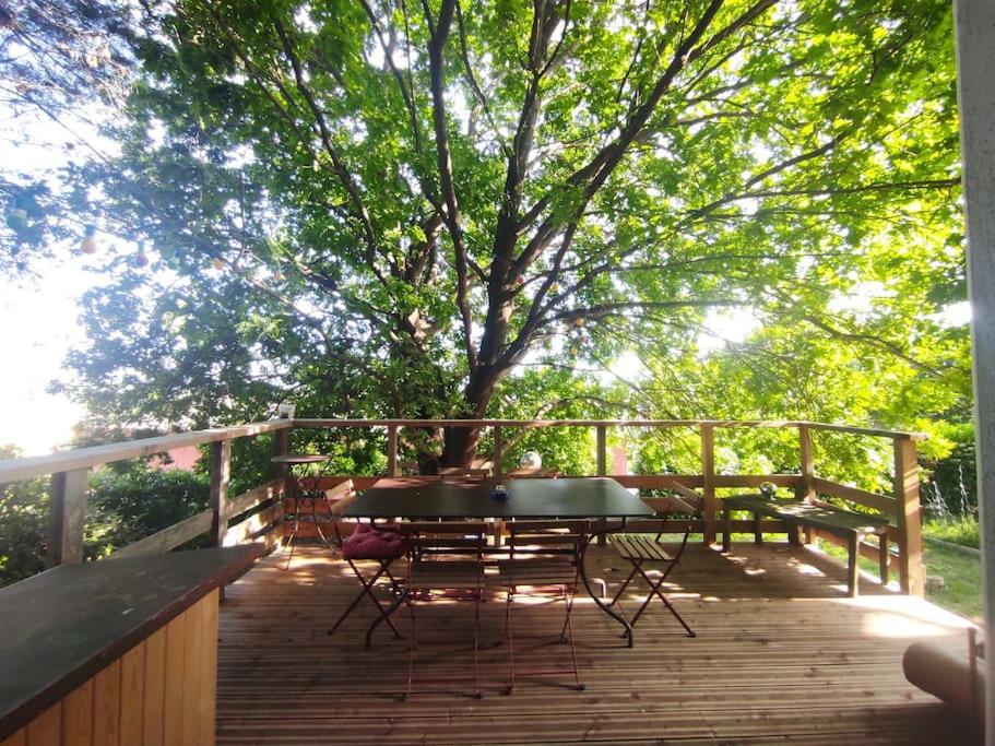 einen Tisch und Stühle auf einer Holzterrasse mit einem Baum in der Unterkunft Tressan:La Calade, maison d'artiste in Tressan