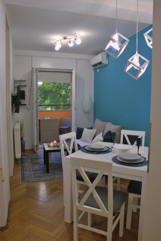 a kitchen and living room with a white table and chairs at Novi Sad Apartman Tenigo in Novi Sad