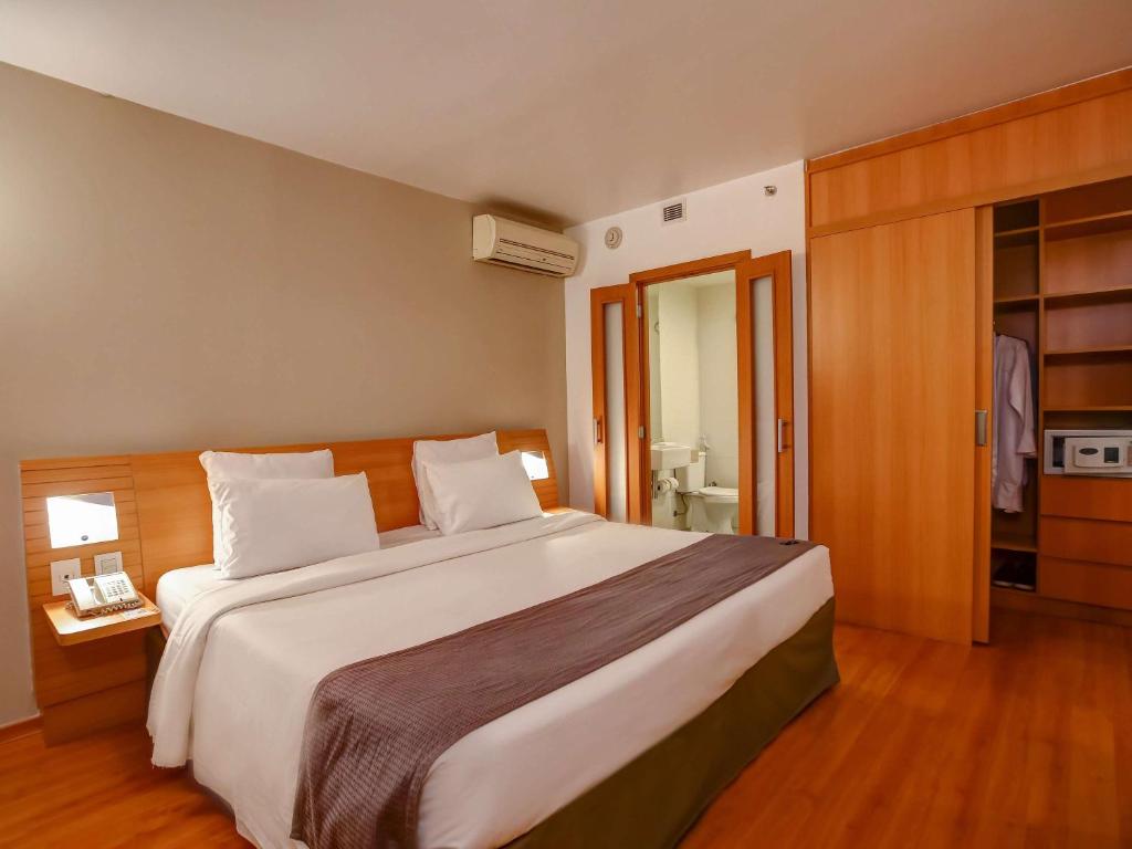 a bedroom with a large bed and a bathroom at Novotel RJ Santos Dumont in Rio de Janeiro