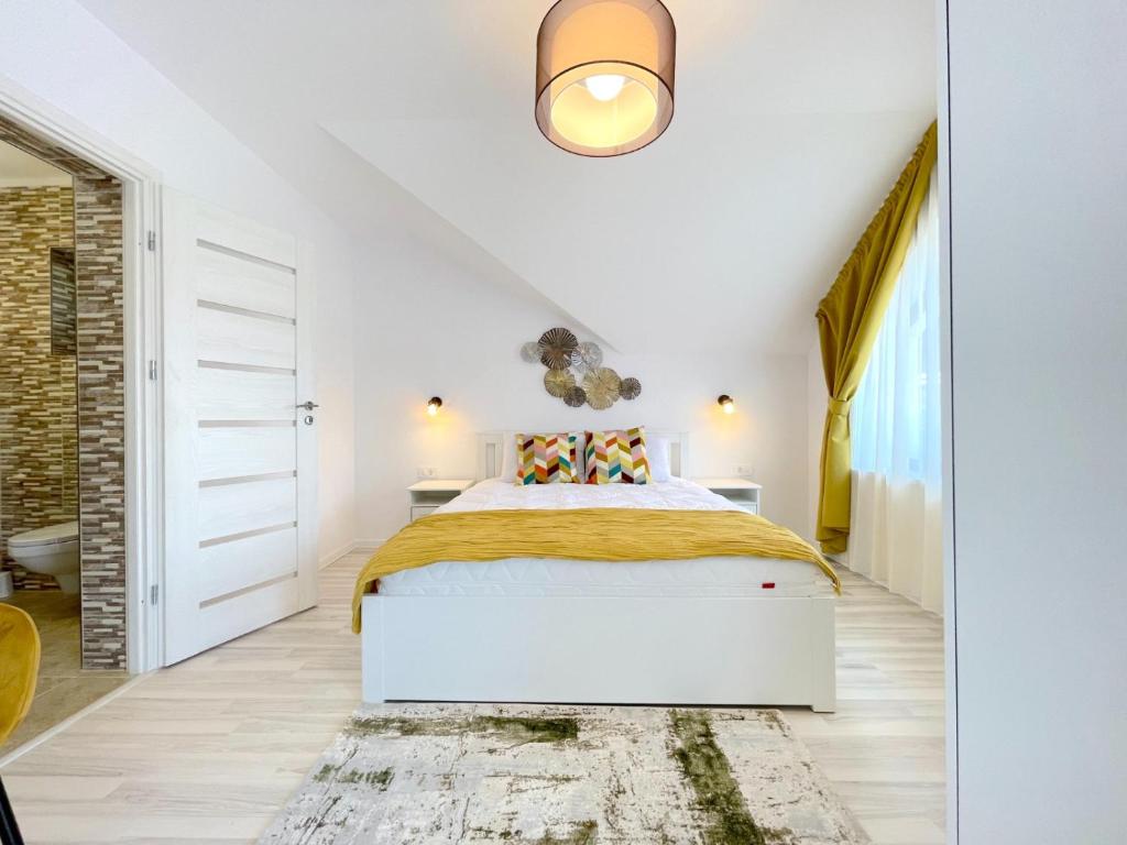 a white bedroom with a bed and a rug at Vila Rolizo in Braşov