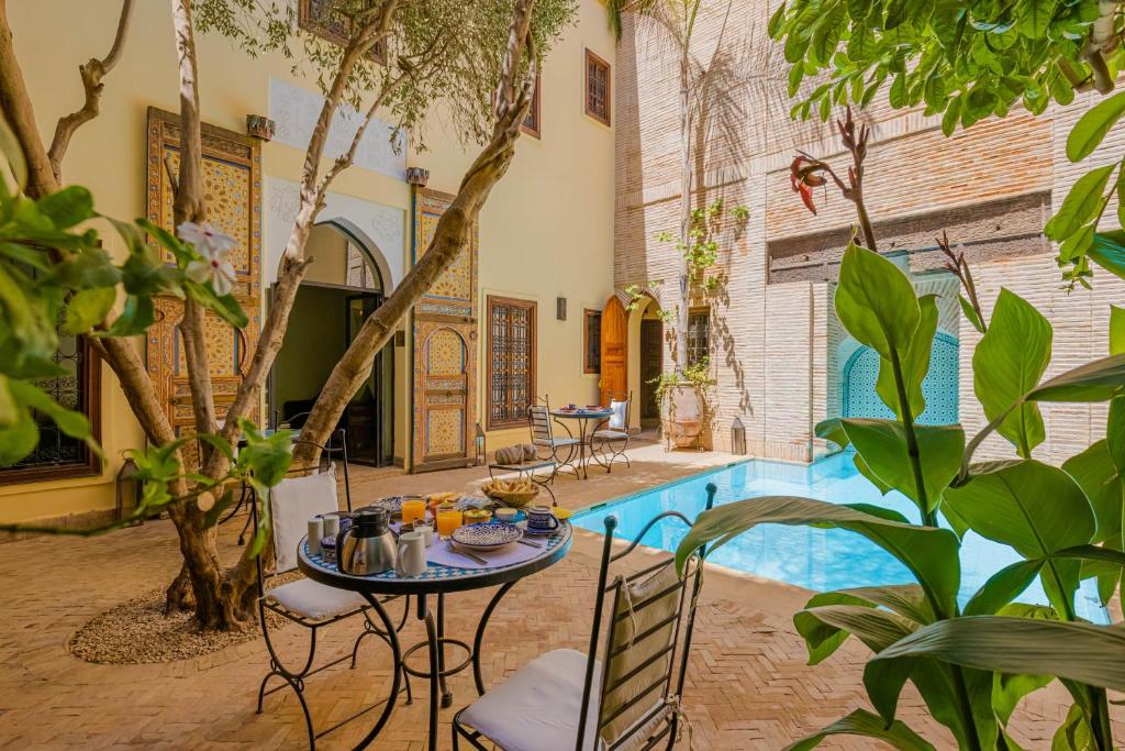 um pátio com uma mesa e cadeiras e uma piscina em Riad Il Parco dei Principi em Marrakech