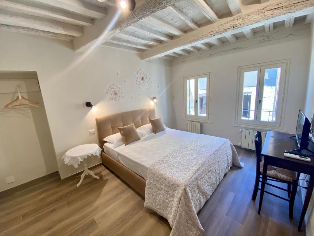 a bedroom with a white bed and a desk and windows at Casa Ambra in Cortona