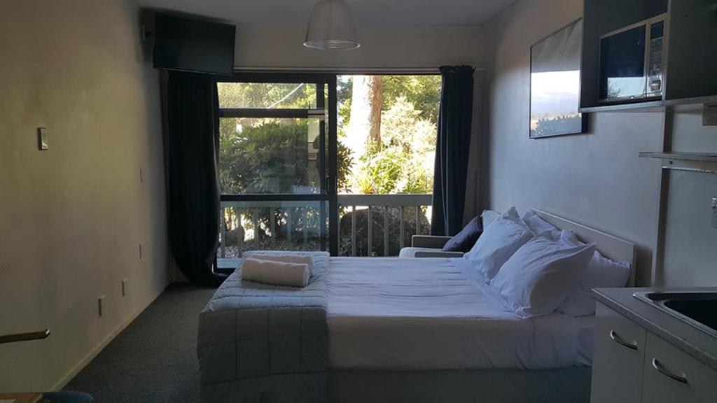 um quarto com uma cama e uma grande janela em Alpine Chalets em National Park
