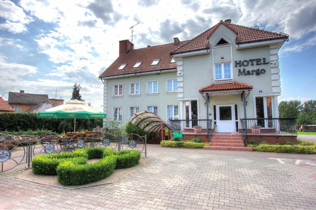 a hotel with tables and chairs in front of a building at Hotel Margo in Cedynia