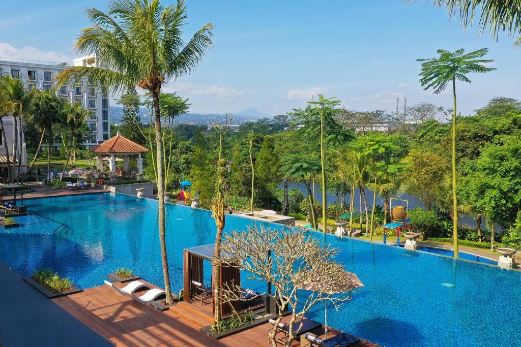 una grande piscina con palme e un edificio di Mason Pine Hotel Bandung a Padalarang