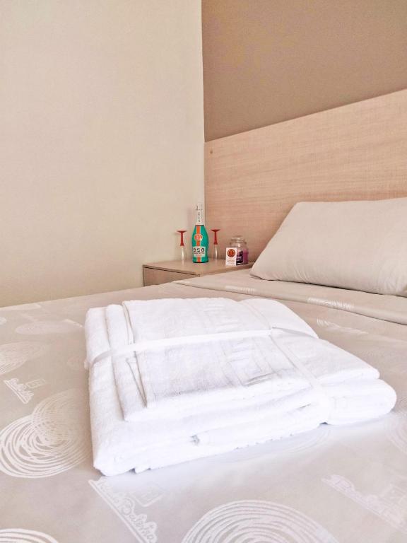 a white bed with a pile of towels on it at Affitti brevi Olimpo Pompei in Pompei
