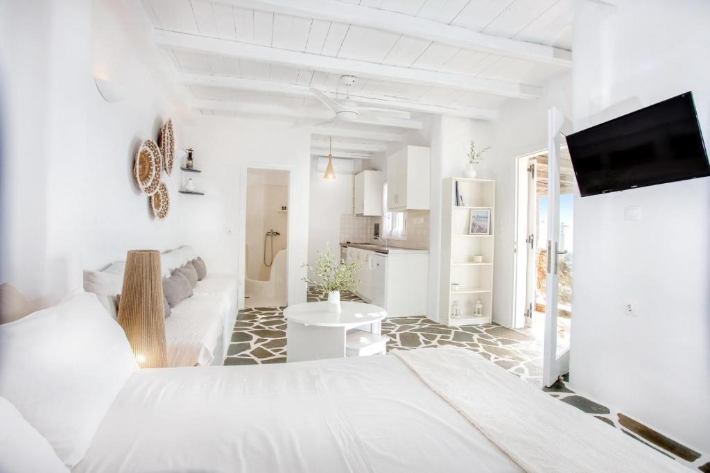 um quarto branco com uma cama e uma cozinha em Penelope Villas em Caristo