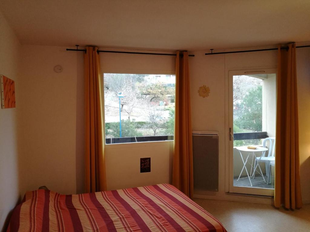 - une chambre avec un lit et une grande fenêtre dans l'établissement Studio "Le Rigaou", à Gréoux-les-Bains