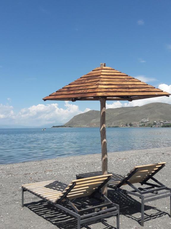 um par de cadeiras e um guarda-sol numa praia em Hotel Today , Խաղաղության լողափ em Shorzha