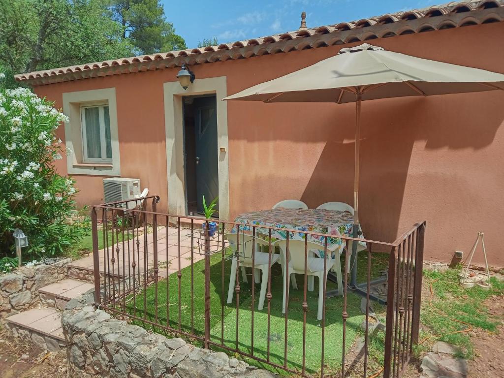 uma mesa com guarda-sol e cadeiras em frente a uma casa em Emilie em Vidauban