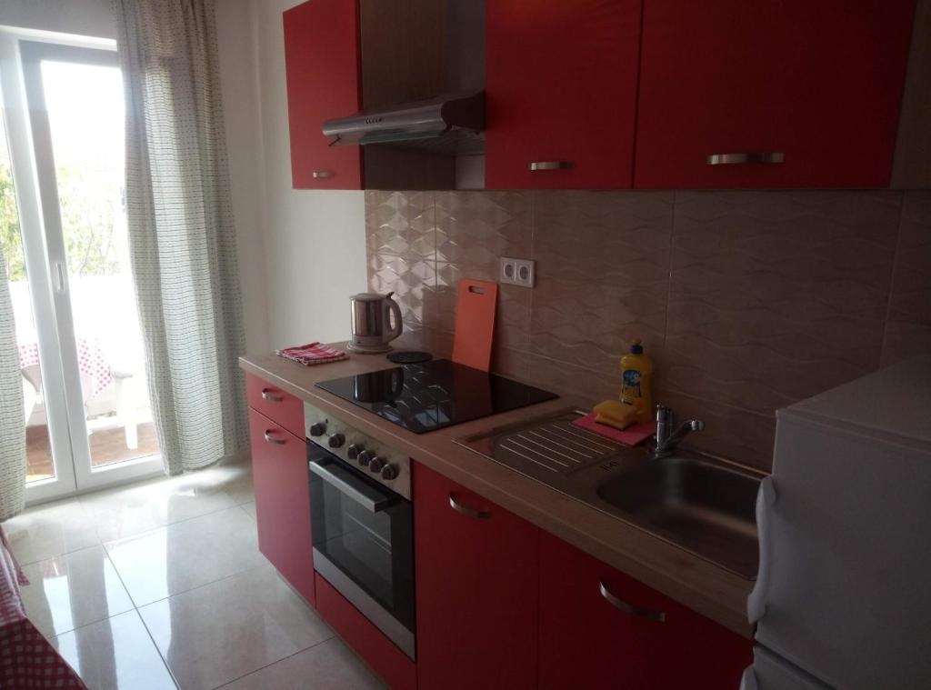 a kitchen with red cabinets and a stove and a sink at Dragica 2 in Palit
