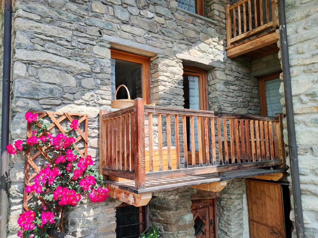 a balcony on the side of a stone building with flowers at Appartamento Chatrian 2 CIR-TORGNON-0019 in Torgnon