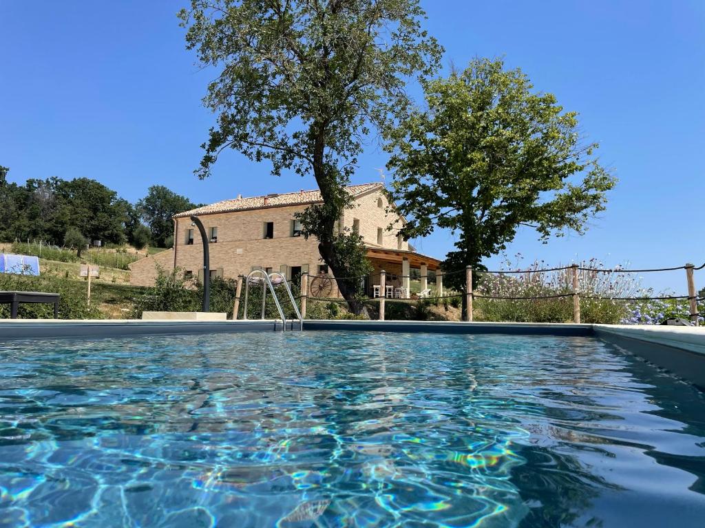 a swimming pool in front of a house at Casale dei Cinque Colli in Ostra