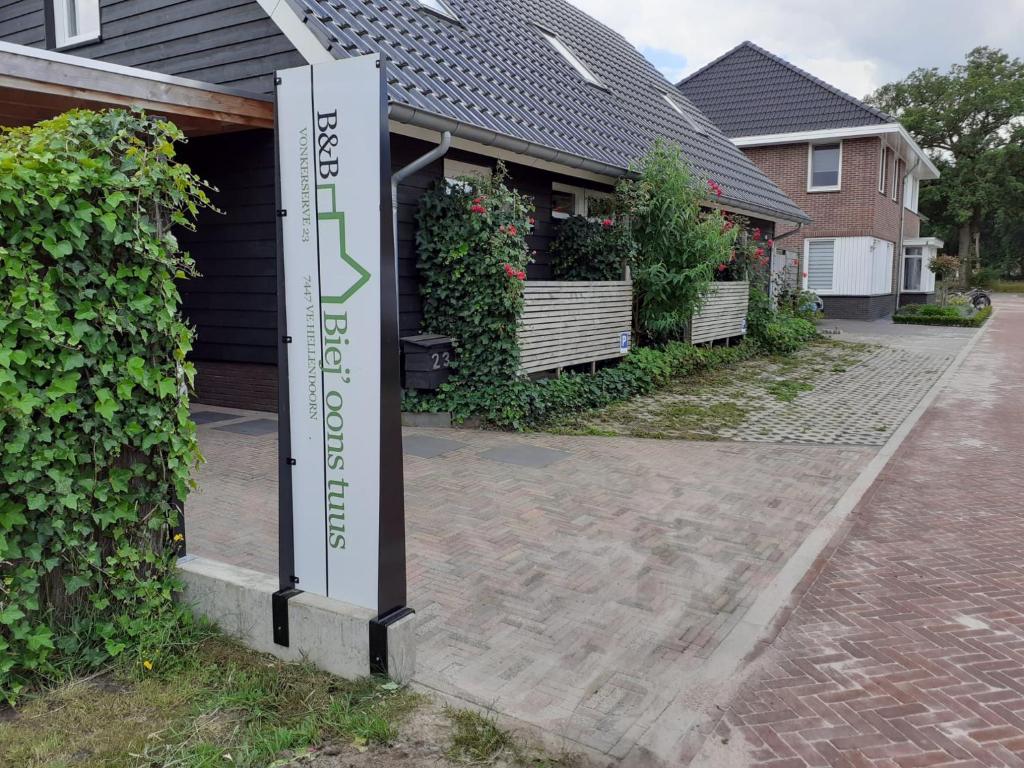 a sign in front of a house with a driveway at B&B Biej' oons tuus in Hellendoorn