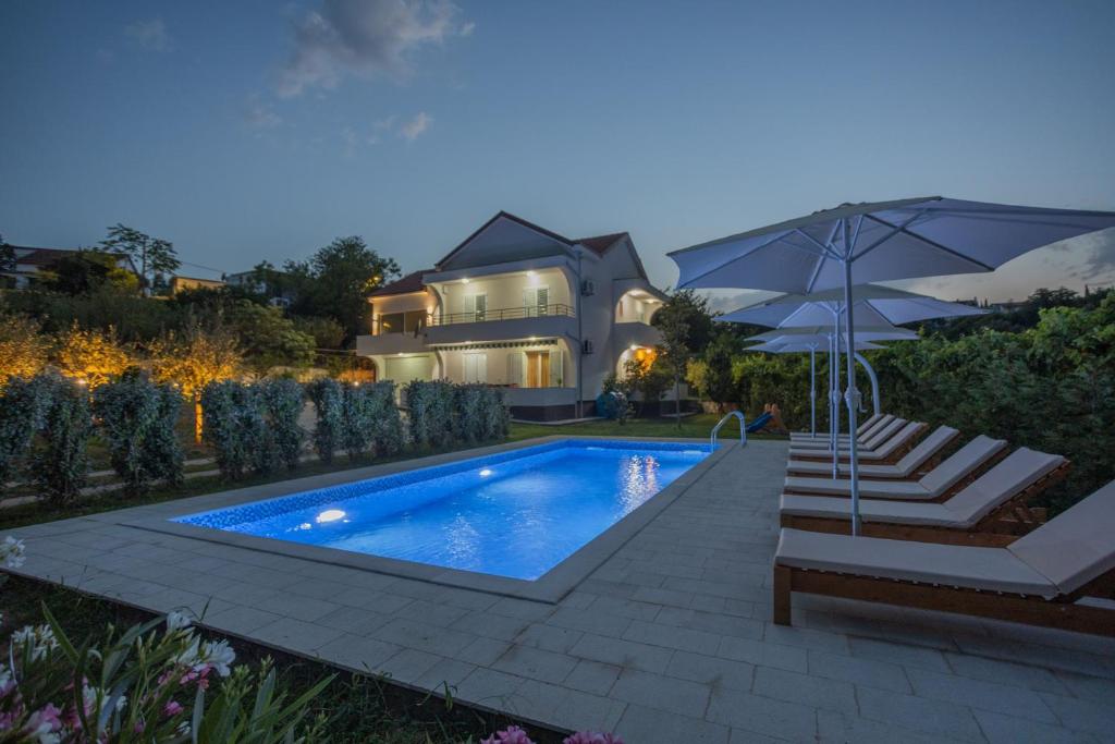 - une piscine avec un parasol et une maison dans l'établissement Villa MontAnja, à Herceg-Novi