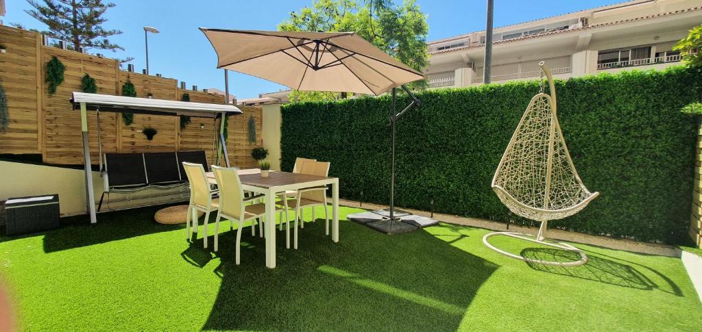 um pátio com uma mesa, uma rede de descanso e um guarda-chuva em Apartamento con jardín y piscina em Marbella