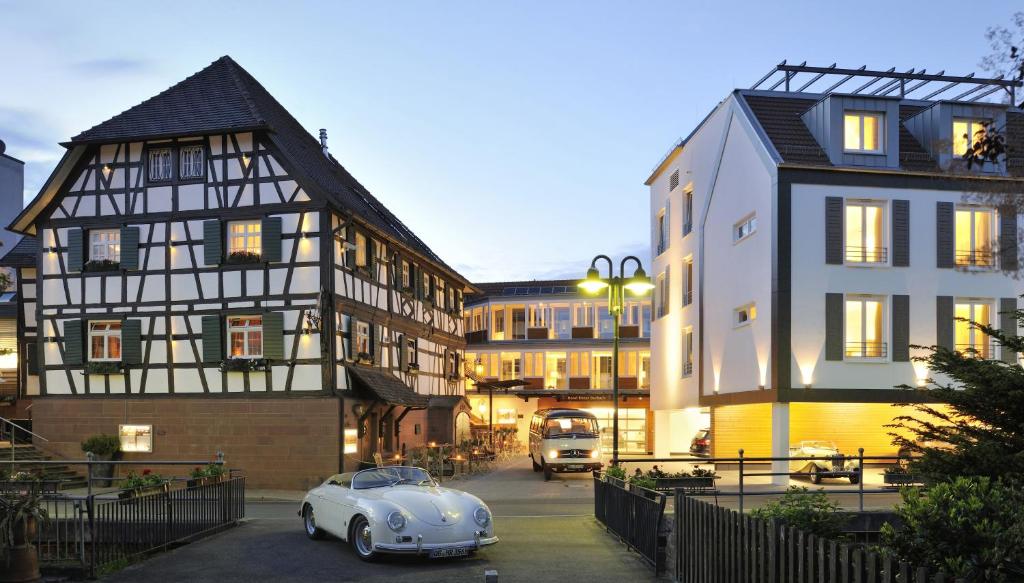 een witte auto geparkeerd op een parkeerplaats naast de gebouwen bij Hotel Ritter Durbach in Durbach