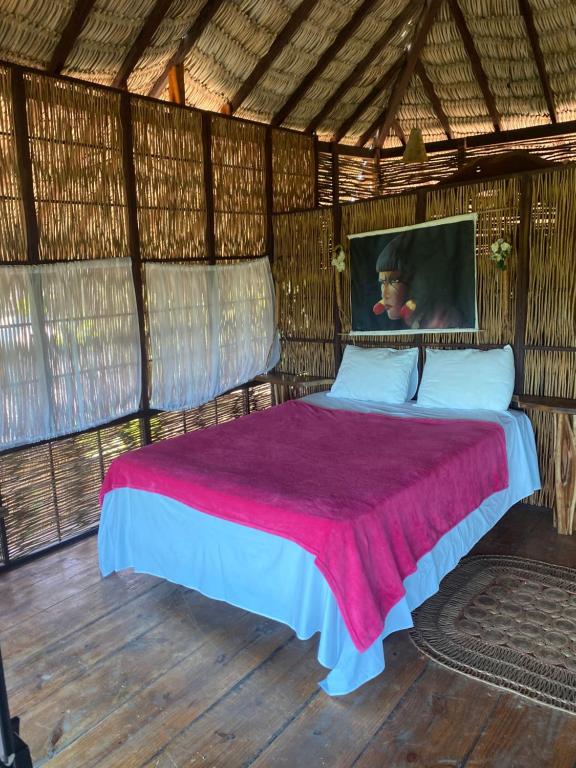 a bedroom with a bed in a straw hut at Casa e bangalôs - Refugio Lodge- Sto Inacio - 3km de Atins in Atins