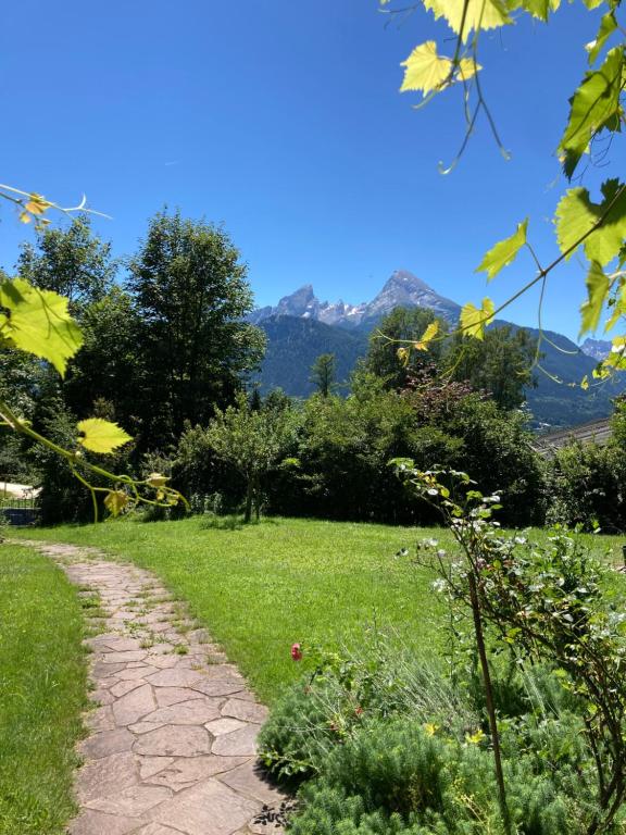 un camino en un jardín con montañas en el fondo en Watzmann, en Bischofswiesen