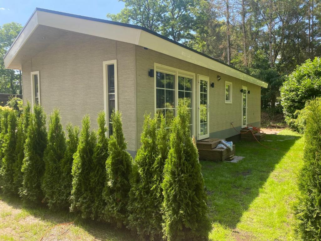 una pequeña casa con árboles delante de ella en Wellness chalet met sauna en Ermelo