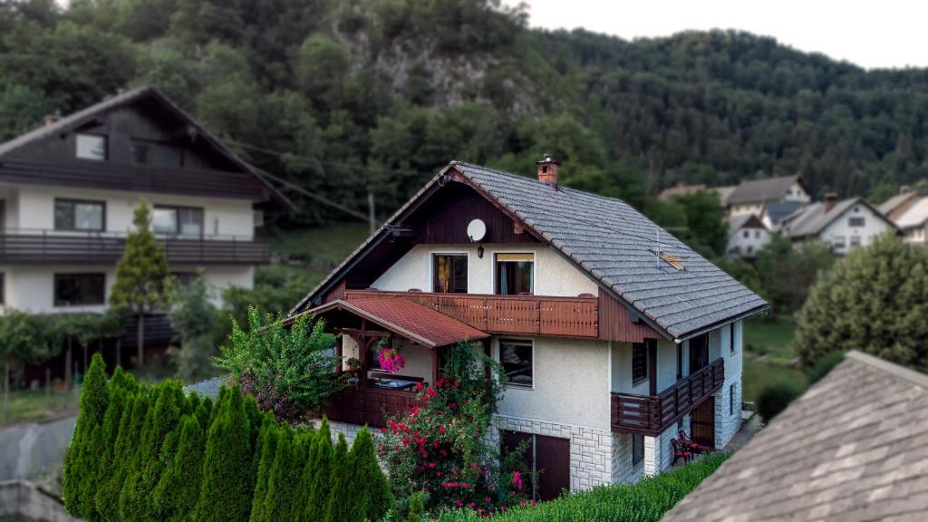 a white house with a brown roof on a hill at Alp House in Bohinjska Bela