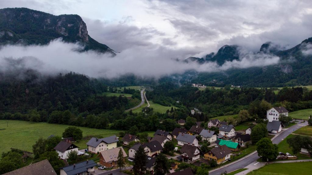 a village in a valley with clouds in the mountains at Alp House in Bohinjska Bela