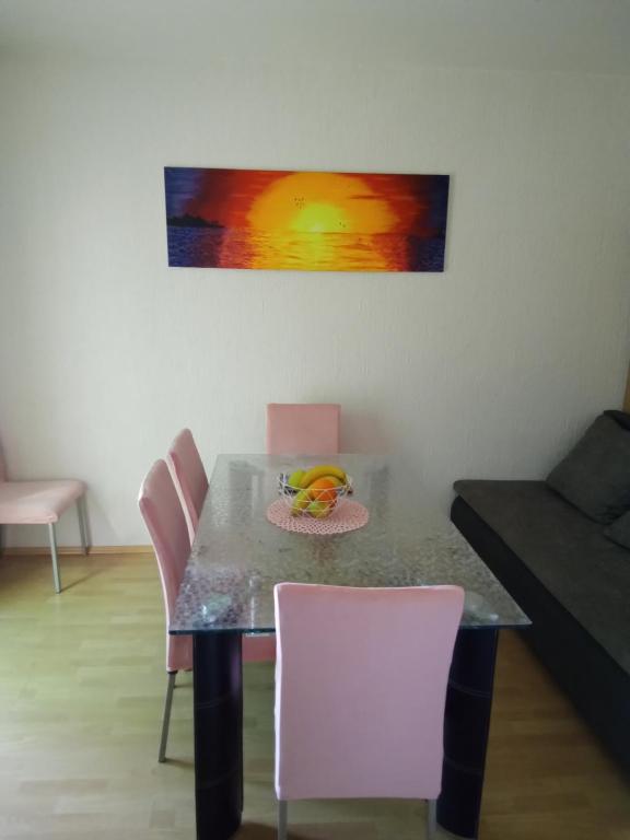 a dining room table with pink chairs and a painting at Apartman Pavic in Pag