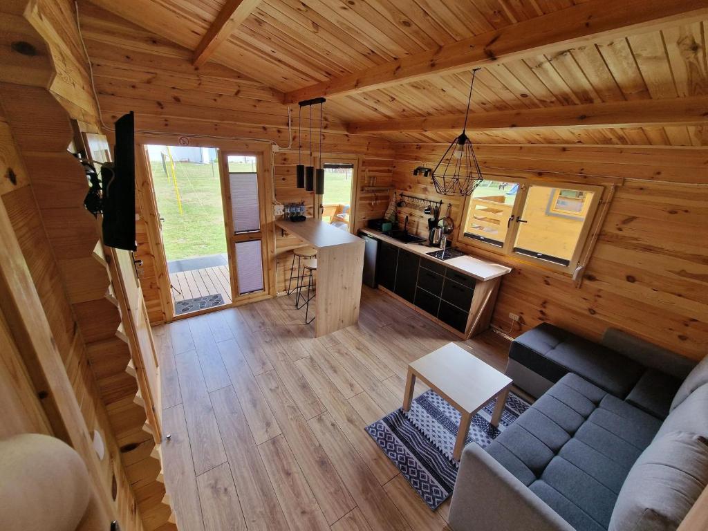 una cabaña de madera con vistas a una sala de estar y una cocina. en DOMKI POD DĘBEM en Grzybowo