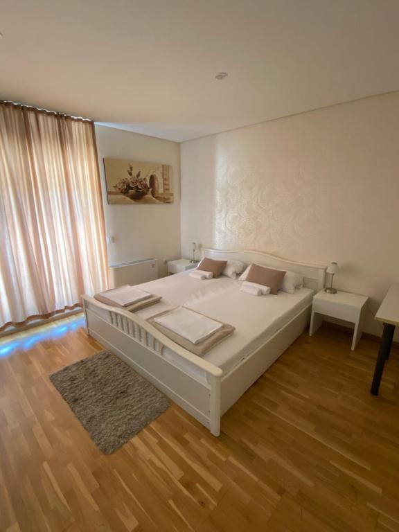 sypialnia z dużym białym łóżkiem i drewnianą podłogą w obiekcie B&B Alex18 w Niszu