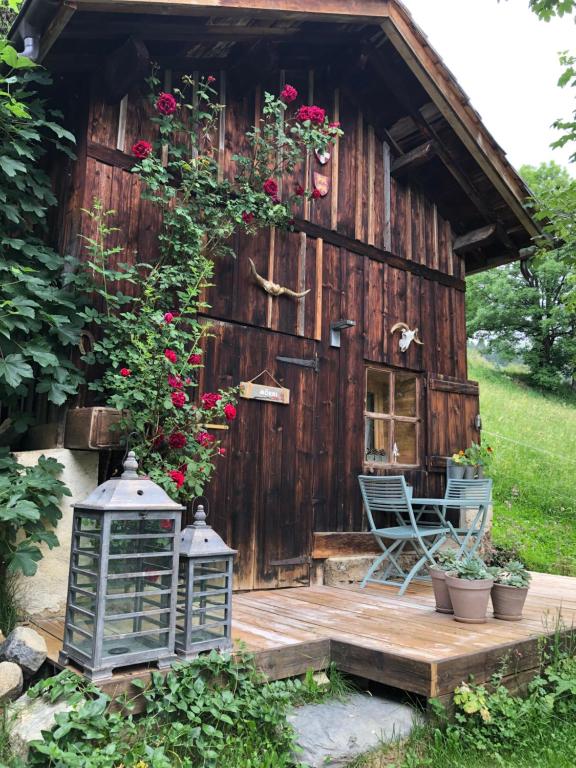a barn with a deck and a chair and flowers at Le Pika in Hauteluce