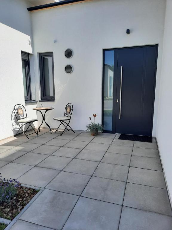 een patio met een blauwe deur en stoelen en een tafel bij Ferienwohnungen Winzergasse in Purbach am Neusiedlersee
