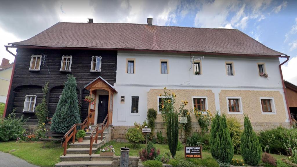 ein großes weißes und schwarzes Haus mit einem Hof in der Unterkunft Ubytování U Sviráků in Srbská Kamenice