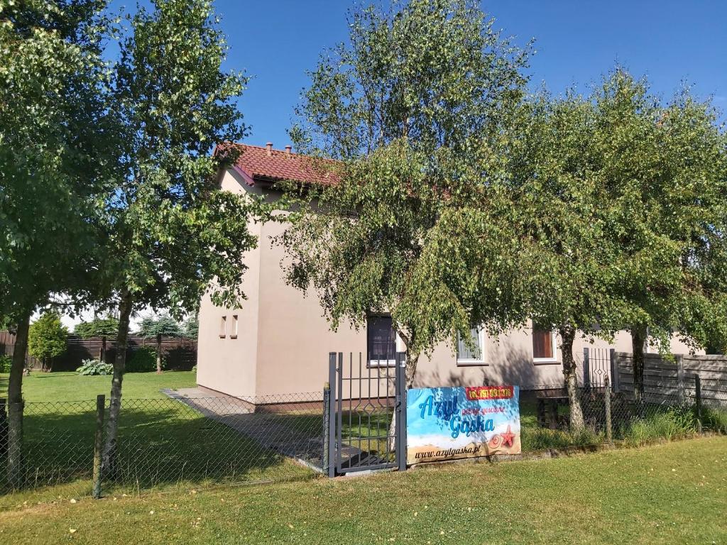 Biały dom z płotem przed nim w obiekcie Azyl Gąska w Gąskach