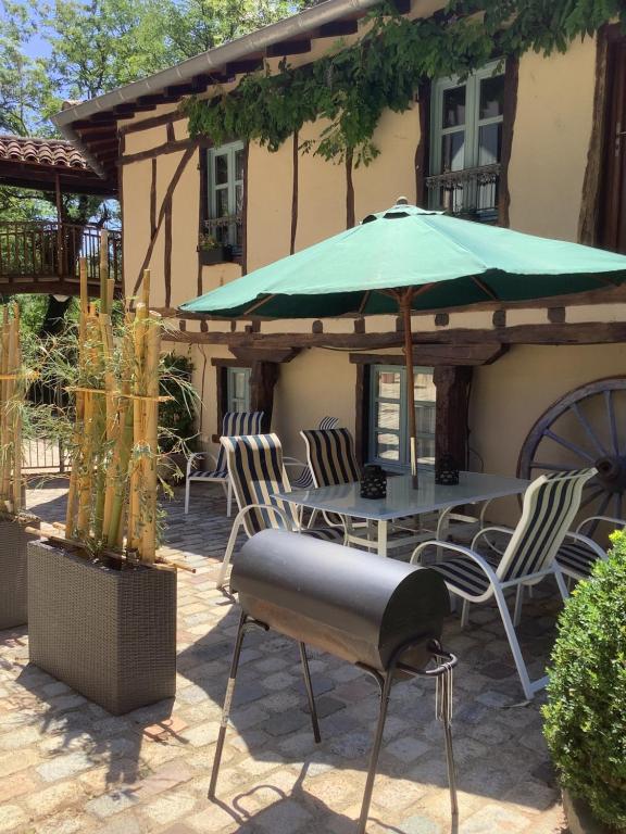 un patio con una mesa con una sombrilla verde en Lovely 2 bedroom gite with shared pool, en Castres
