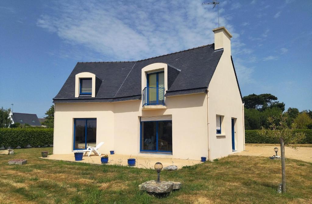 une maison blanche avec un toit noir dans l'établissement Maison familiale jardin à 700m des plages Ty Nowen, à Trégunc