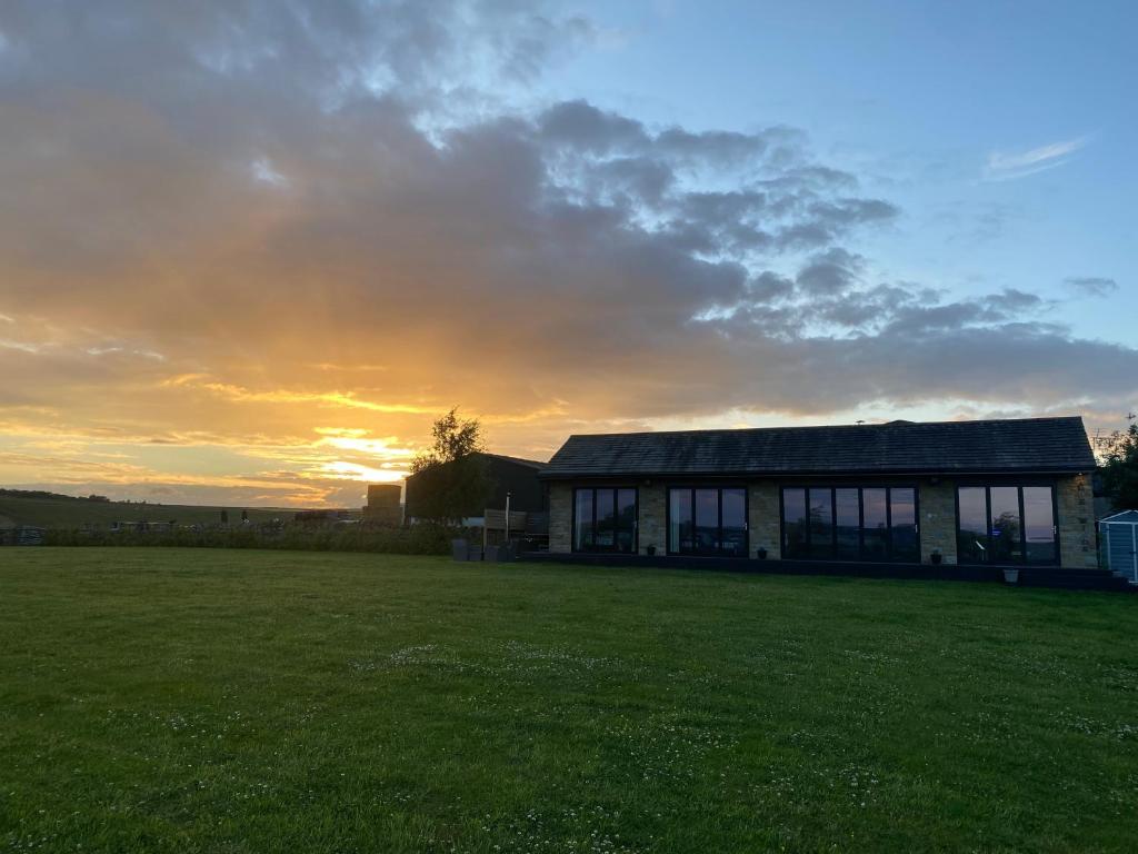 a house in a field with a sunset in the background at Three-winds-guesthouse in South Crosland