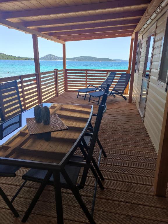 a porch with chairs and a table on the water at K9 Mobile Home Camp Imperial Vodice in Vodice