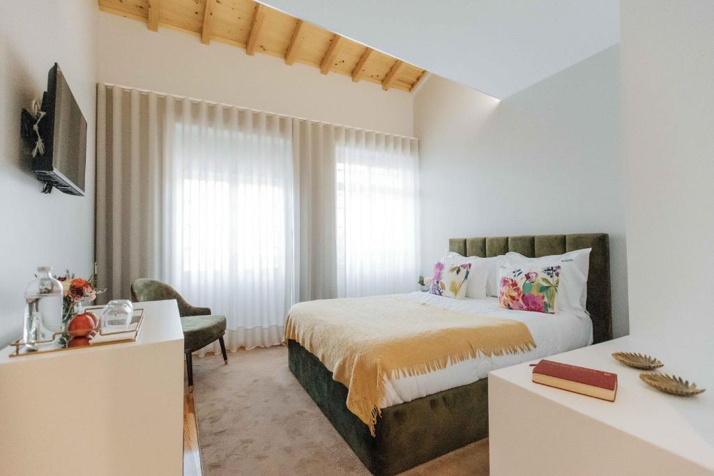 a hotel room with a bed and a dresser at Trovador City Guest House in Guimarães