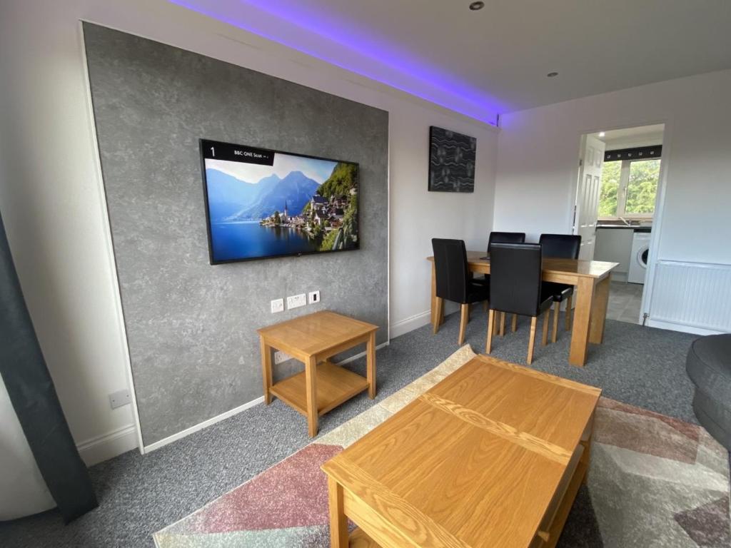 een woonkamer met een tafel en een tv aan de muur bij Pure Apartments Fife - Dunfermline - Pitcorthie in Dunfermline