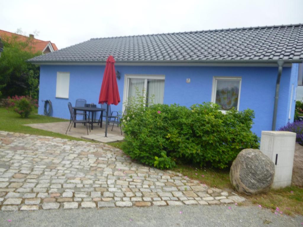 a blue house with a table and a red umbrella at Haus Lavendel in Lancken