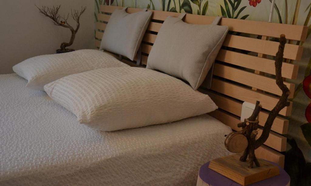 1 cama con almohadas blancas y cabecero de madera en Le gîte du petit branché, en Mazan