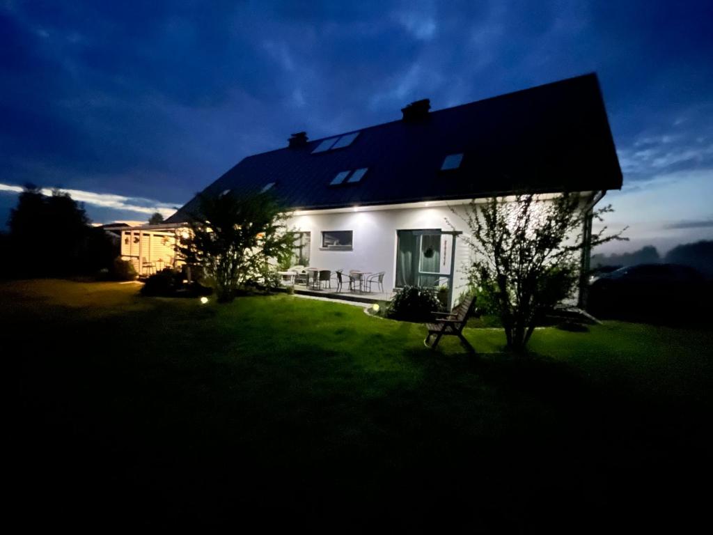 a white house with a bench in the yard at Dom w Trawach in Smołdziński Las