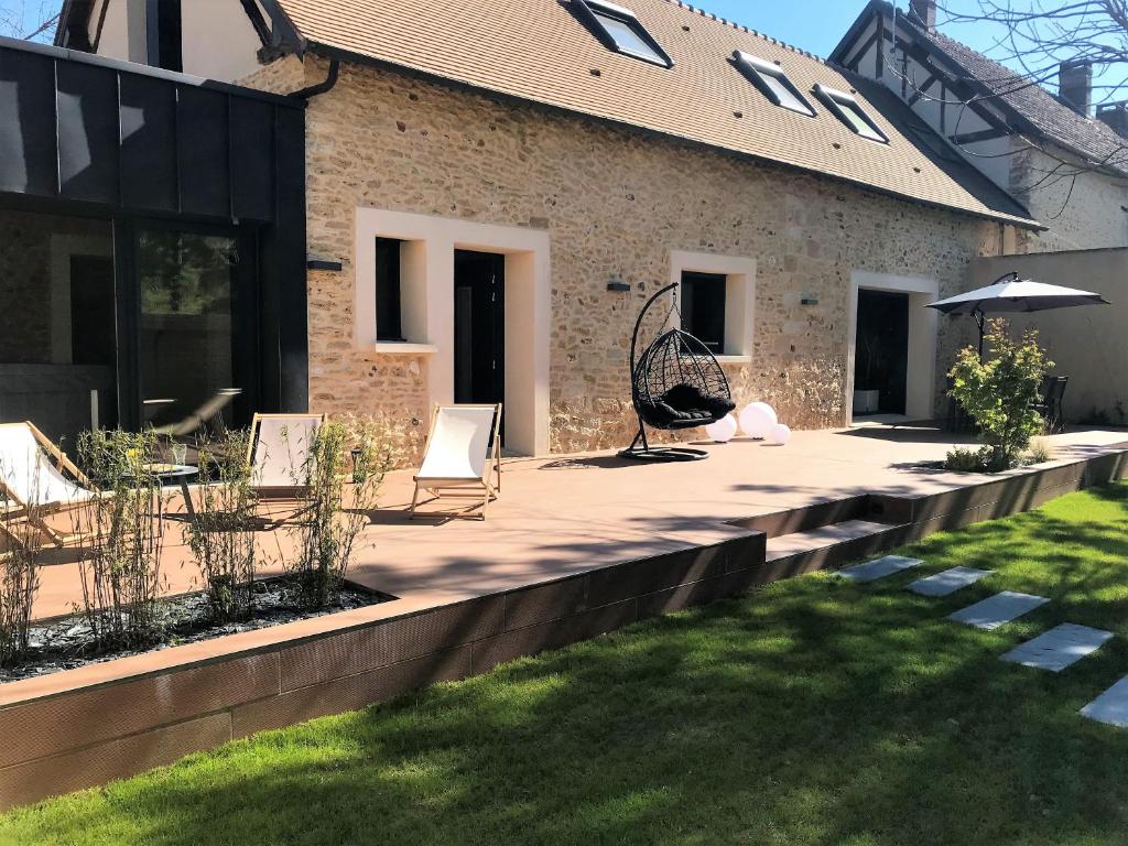 eine Terrasse mit Stühlen und einem Sonnenschirm auf einem Haus in der Unterkunft Gite de la Prée SPA luxe proche Giverny et bord de l'Eure in Ménilles