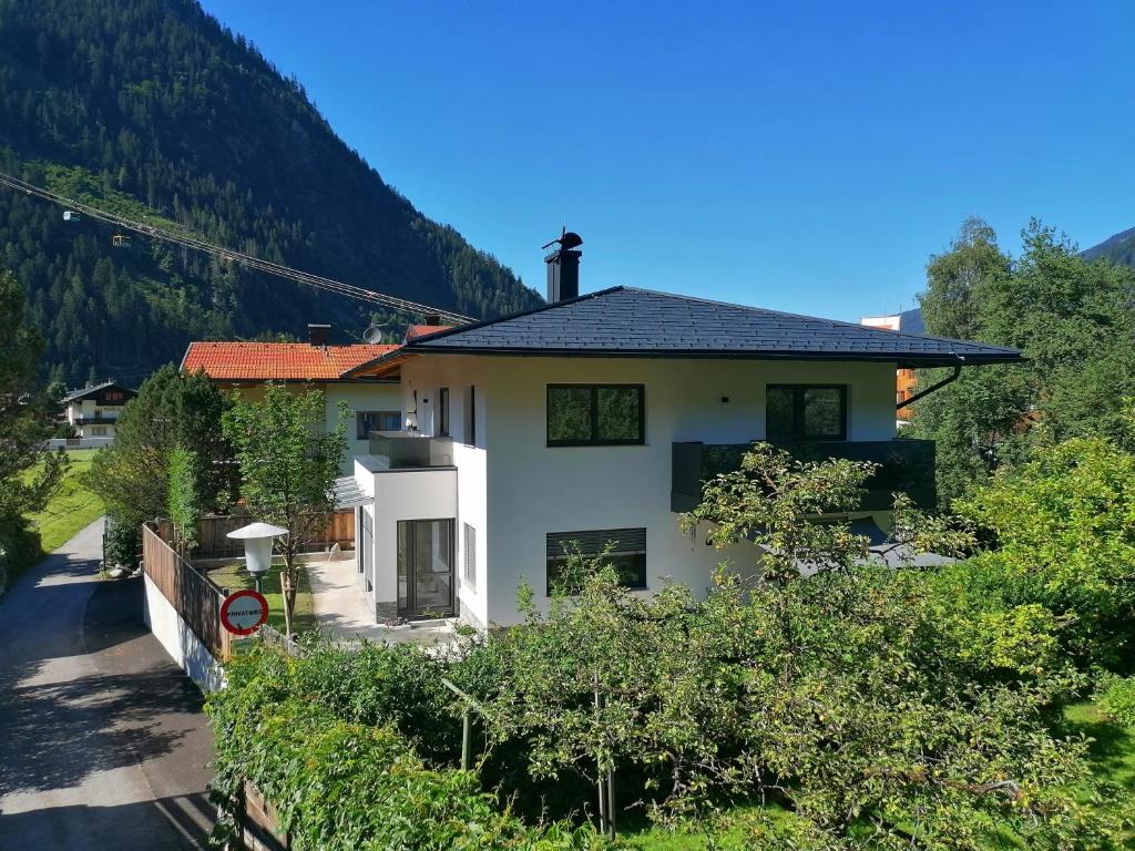 une maison blanche avec une montagne en arrière-plan dans l'établissement Apart Lisa, à Mayrhofen