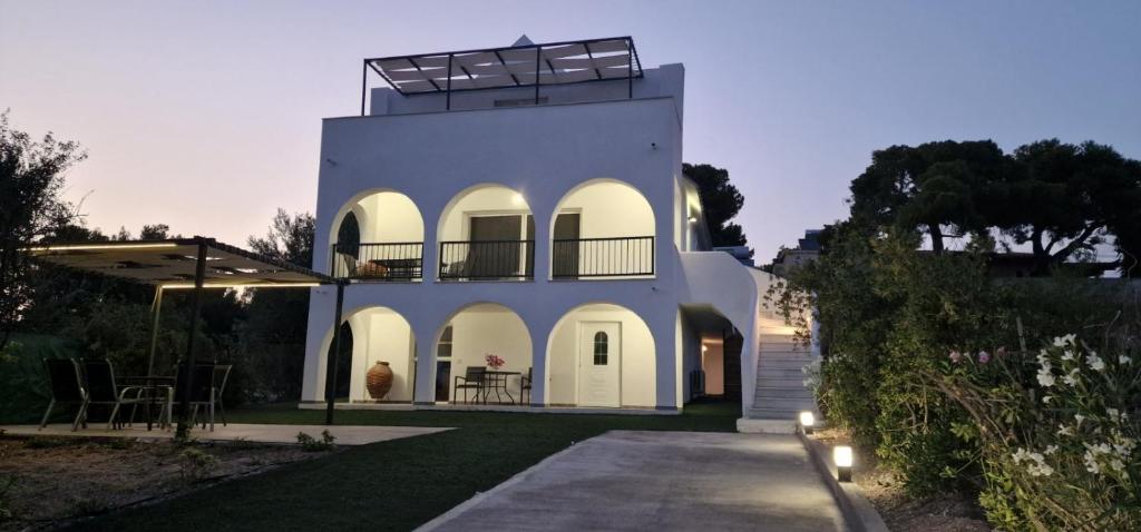 uma casa branca com um alpendre e um pátio em Villa Madenia em Porto Heli