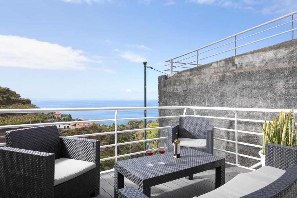 a patio with two chairs and a table on a balcony at UP THE HILL, Conforto e bem estar in Ponta do Sol