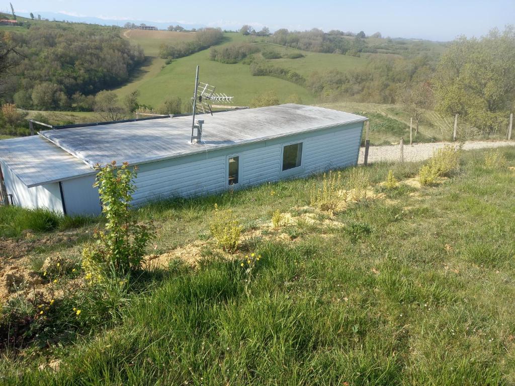 un edificio azul con techo de metal en un campo en ferme de castel pouzouilh, en Le Fossat