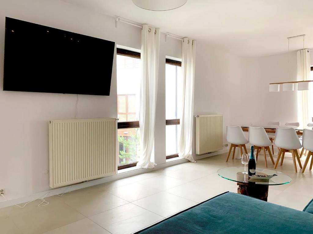 un salon avec une télévision à écran plat sur un mur dans l'établissement Baltica Heaven - Apartament dwupoziomowy przy plaży, à Rogowo