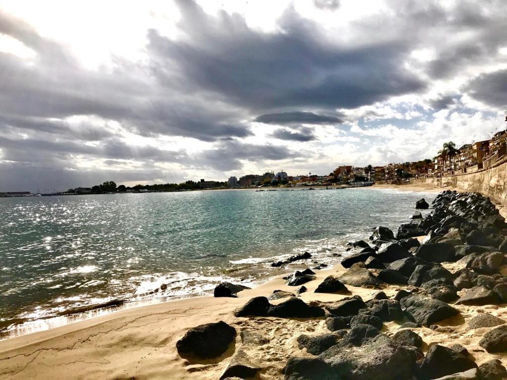 a beach with rocks and the ocean on a cloudy day at Halawa Room Giardini Naxos in Giardini Naxos